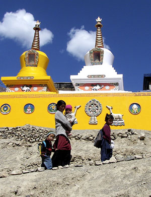 A mother accompanies her children to school just beyond the colorful stupas.